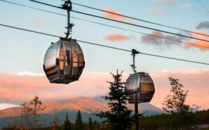 Two gondola cabins glide across a sunset sky, in front of a mountain at Steamboat Ski Resort