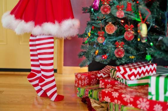 A child stands on tip-toe by a Christmas tree