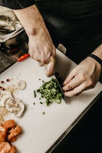 A chef's hands chopping vegetables. Showing ingredients used for making chili (mushrooms and onions) as part of the Chili Challenge when looking for Fall food in Steamboat Springs