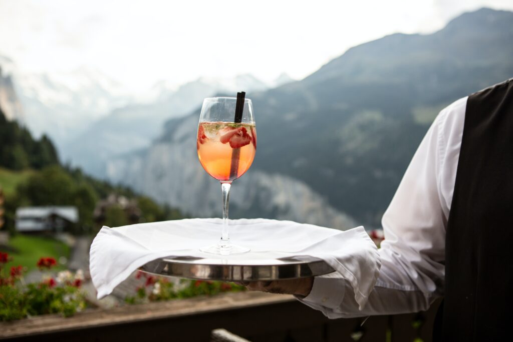 A waiter serves a cocktail with a mountain in the background