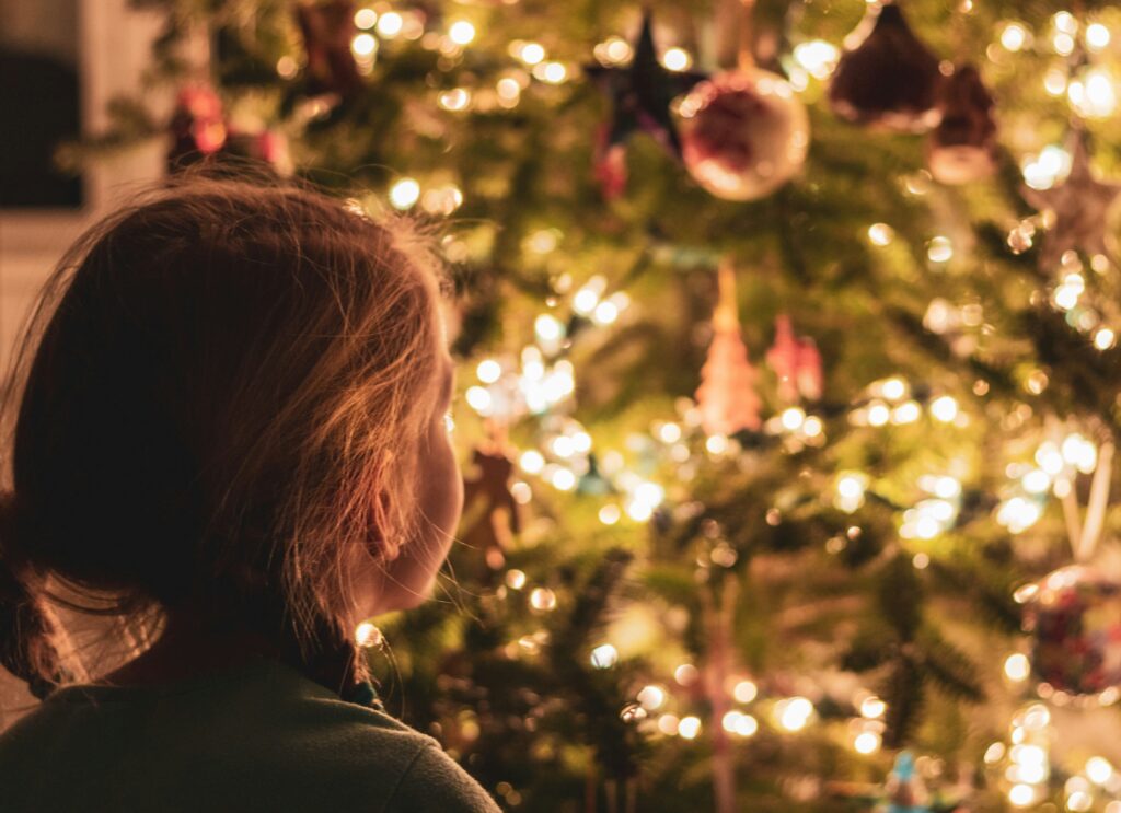 A child looking up at a sparkling Christmas tree