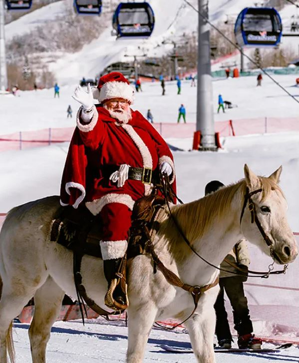Santa waves, whilst riding a grey horse
