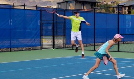 Two people playing mixed doubles tennis