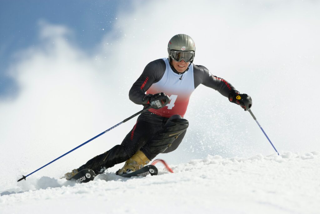 A skier races down a slope with powder flying behind them
