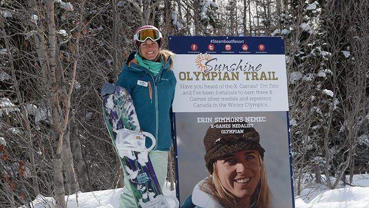 Olympian Erin Simmons Nemec stands with her sign on the sunshine olympian trail
