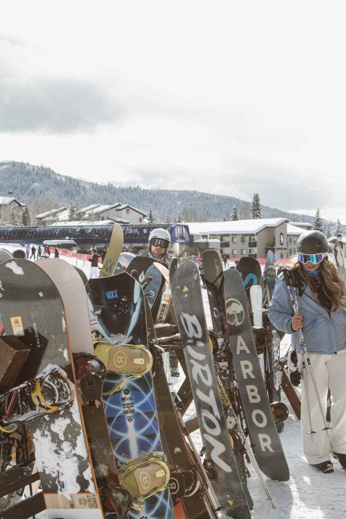 A snowboarder stands proudly next to a line of snowboards