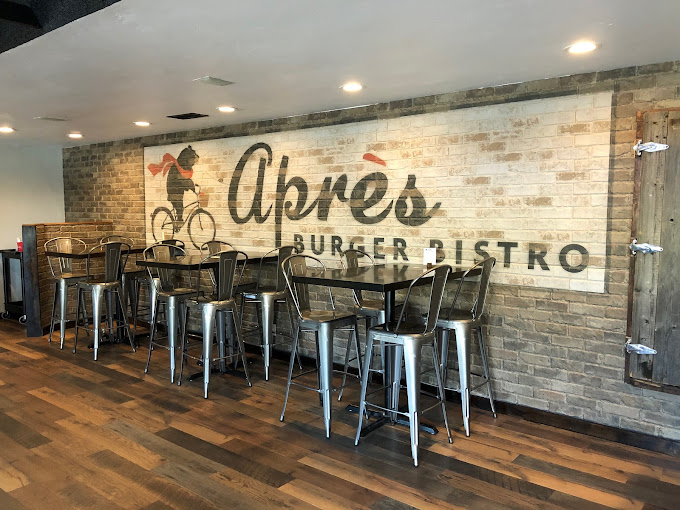The interior of apres burger bistro, with an exposed brick wall and dining tables
