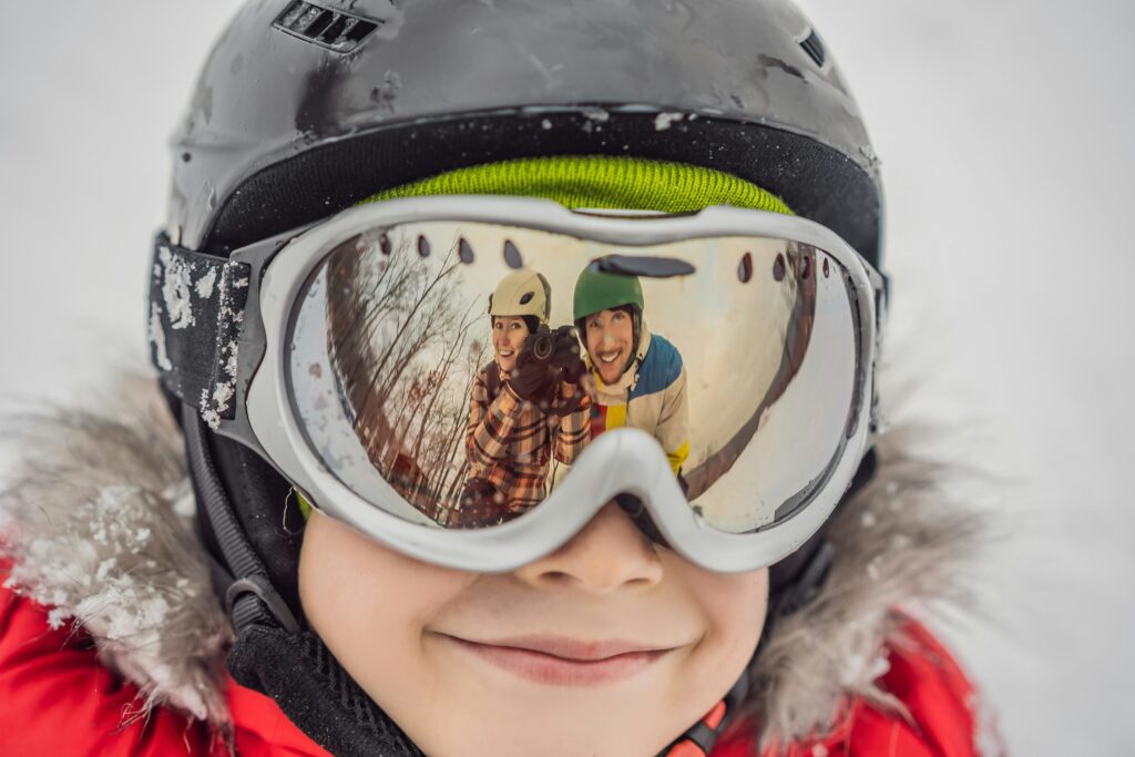 A child in a helmet and ski goggles smiles