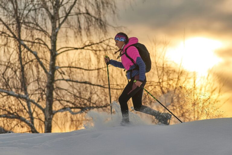 A snow-shoer walks in front of a sunset