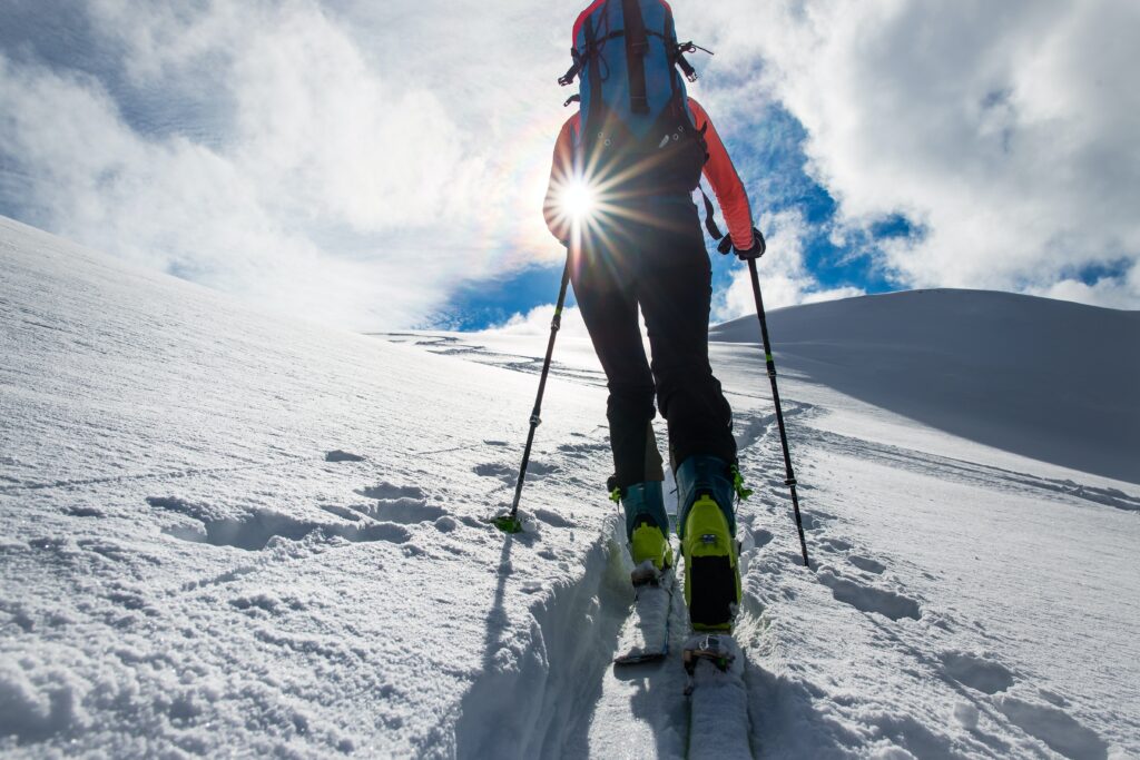 A cross country skier walks towards the sun