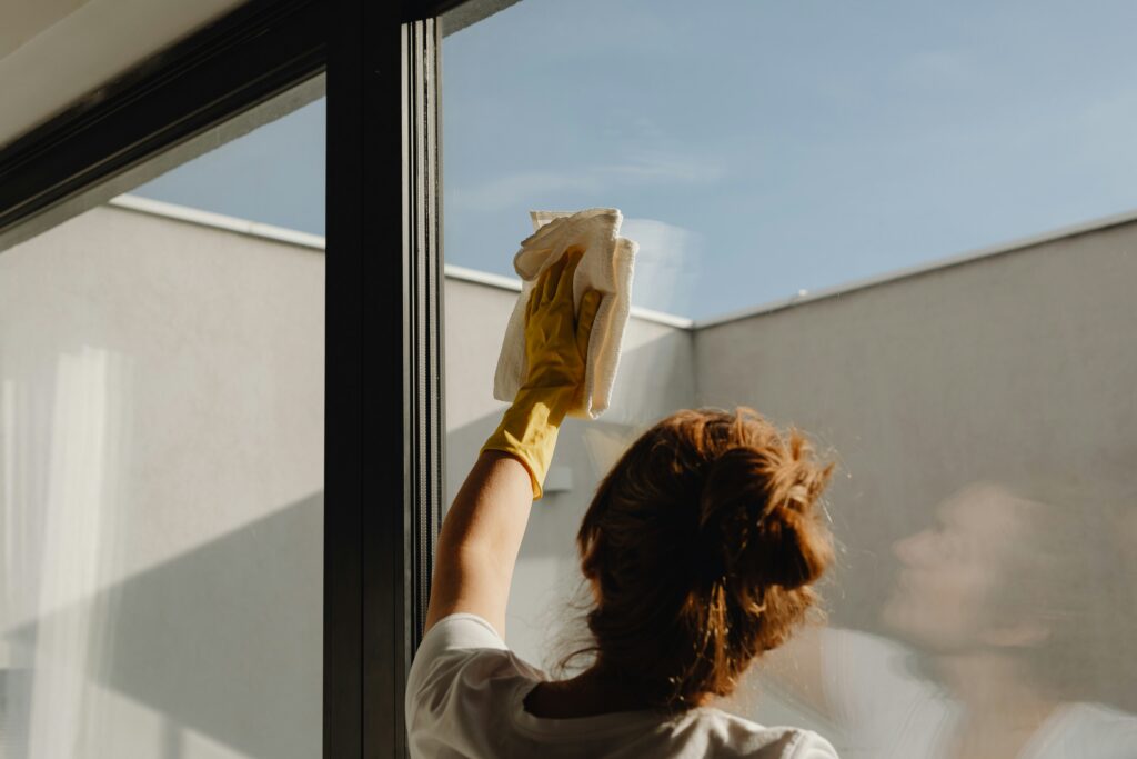 A housekeeper cleans a window