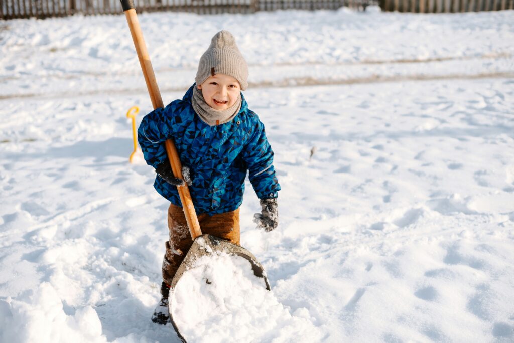 A young boy shovels snow