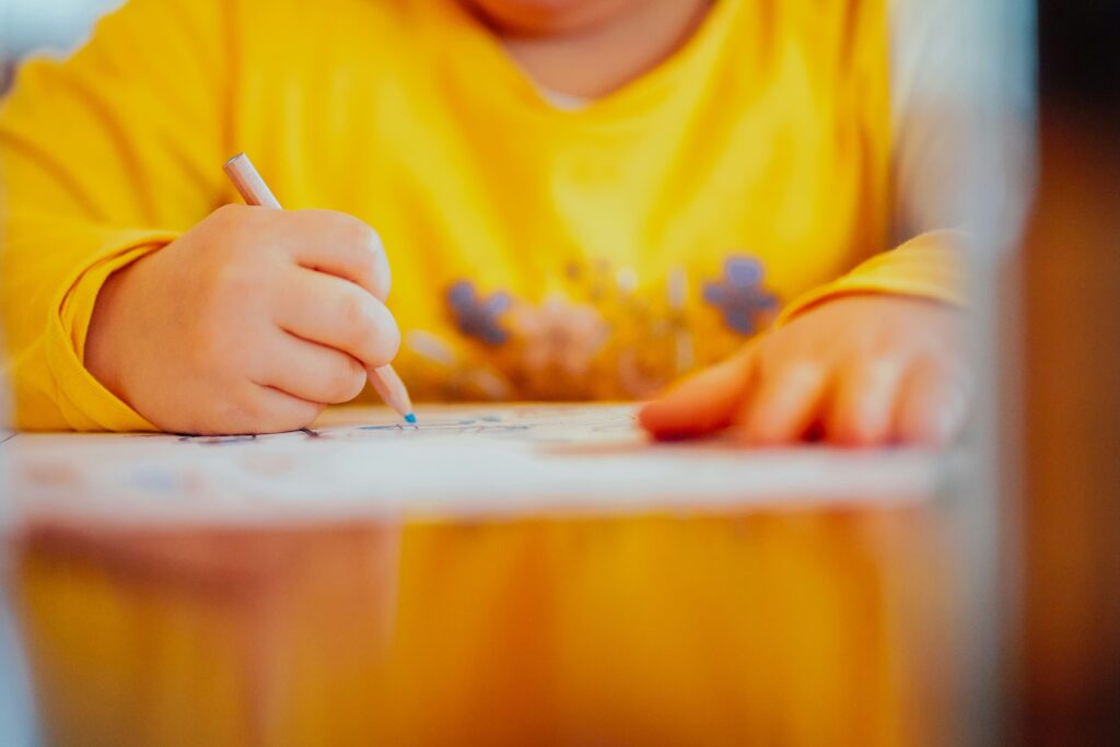 A child in a yellow sweatshirt drawing