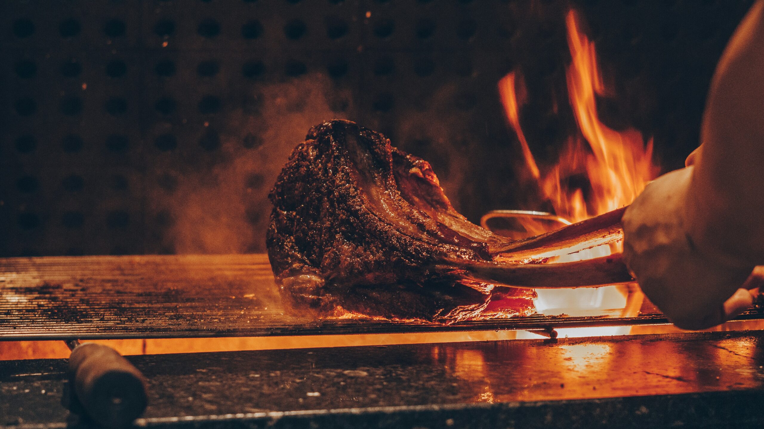 An enormous slab of meat being cooked on a fiery grill