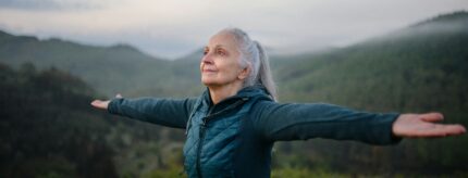 A woman outstretching her arms, backdropped by lush greenery