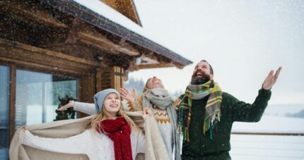 Parents and their daughter laugh in the snow