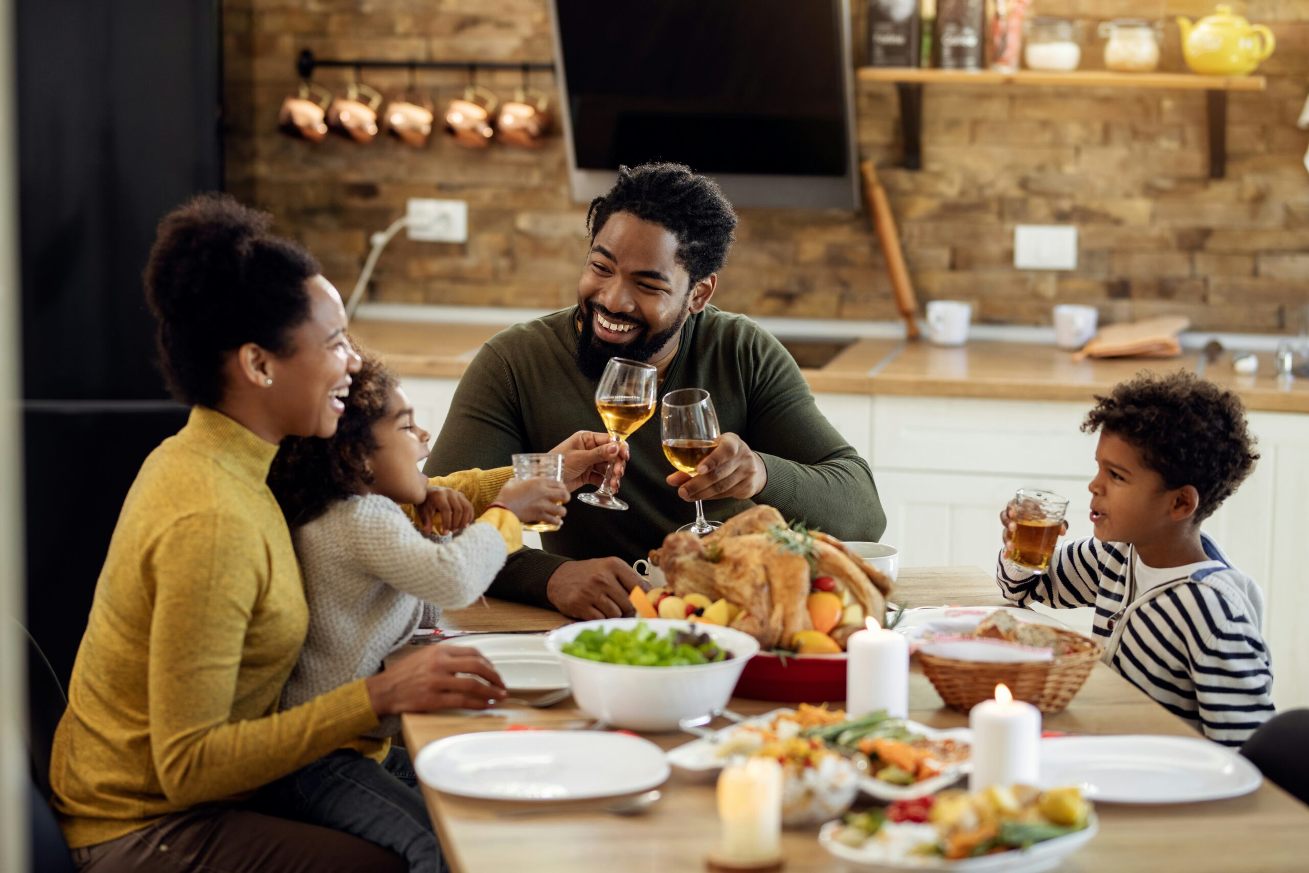 Two parents and two children laughing as they eat a meal together