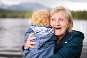 A grandmother cuddles her grandchild next to a lake