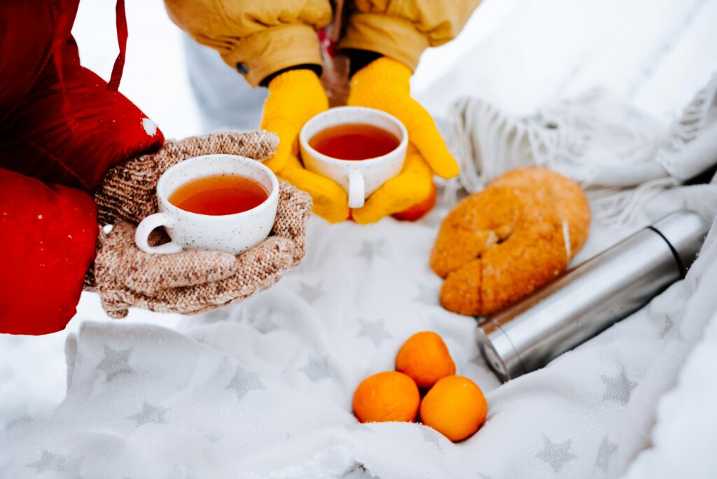 A couple's hands holding tea and having a picnic in the snow