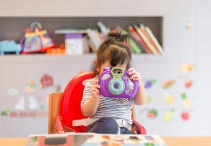 A child playing indoors with a toy camera