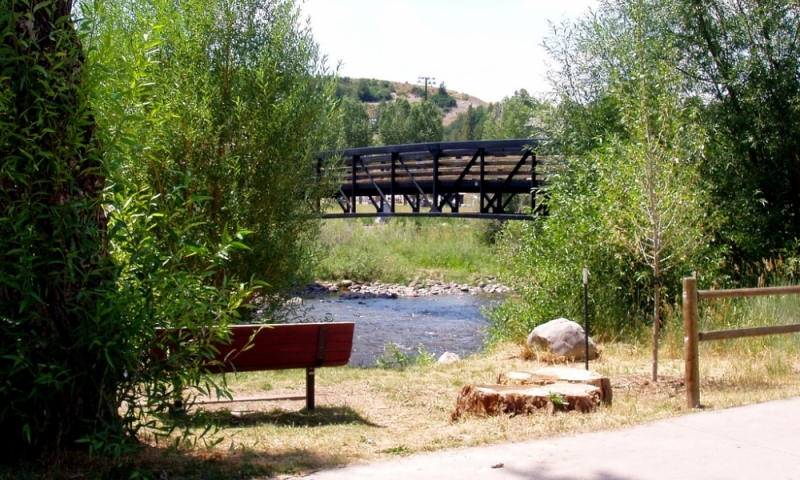A bench and bridge along the Yampa River Core Trail