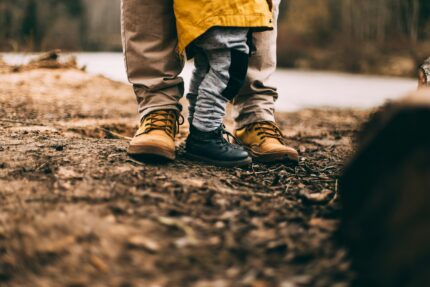 A child and adult's feet on a muddy hiking trail