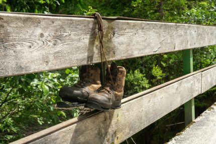 Two hiking boots hanging by their laces on a bridge