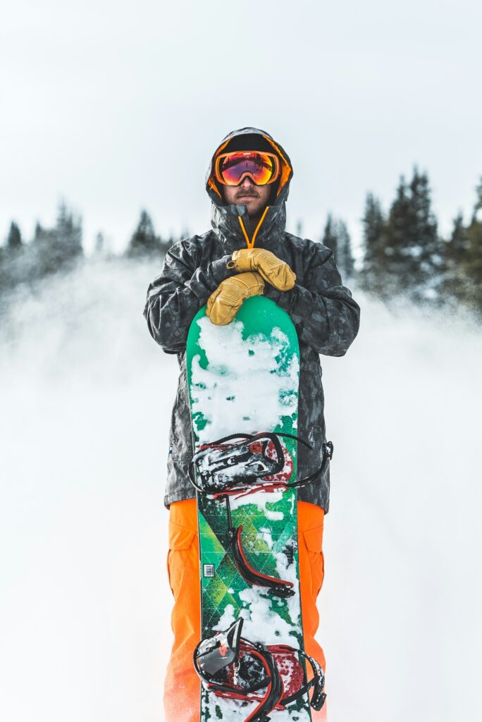 A snowboarder posing with his snowboard