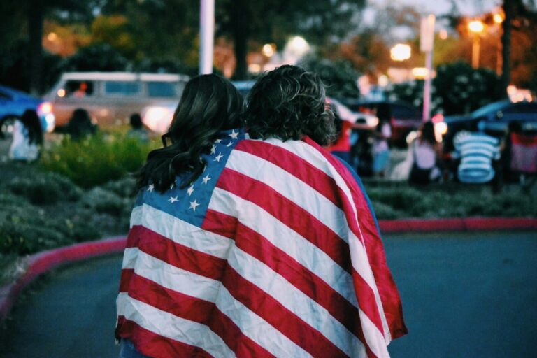 Two women with the stars and stripes flag draped around them
