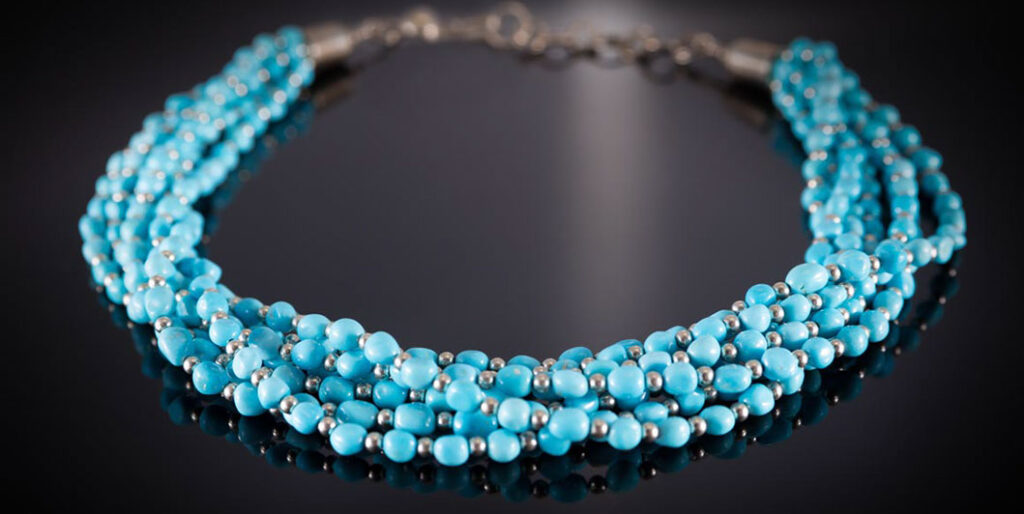 A turquoise necklace on a black table 