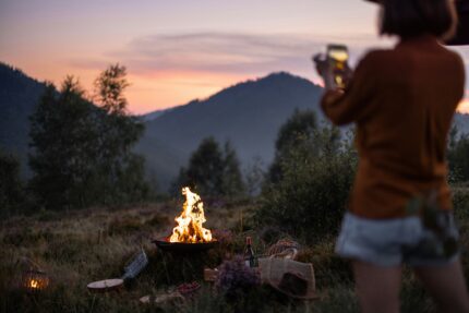 A woman and a campfire on a mountain at nighttime