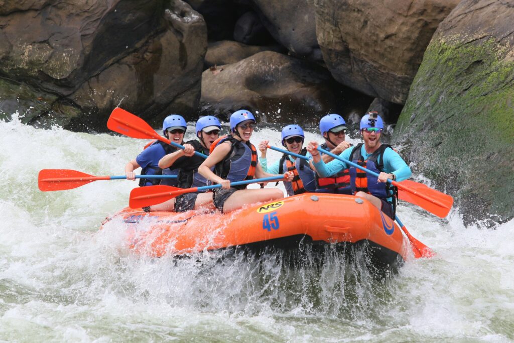 A group on a large orange raft splashing through water