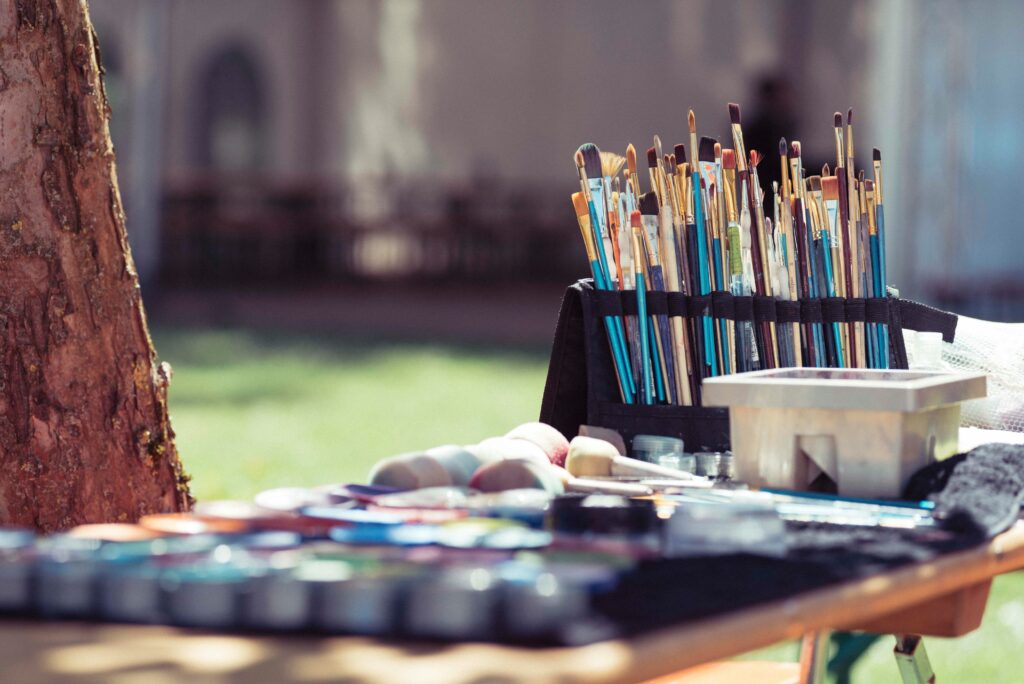 Paint and paintbrushes set on a table outside