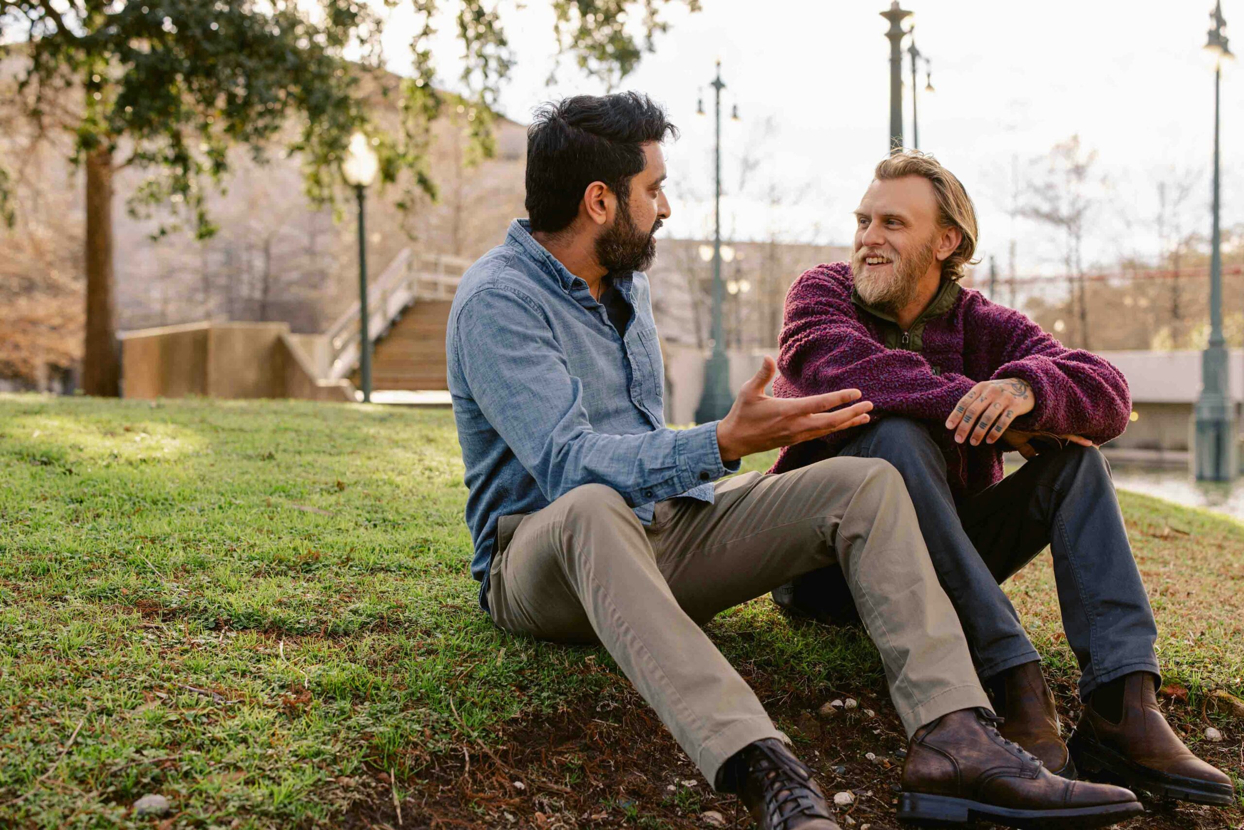 Two men chatting while sat on grass