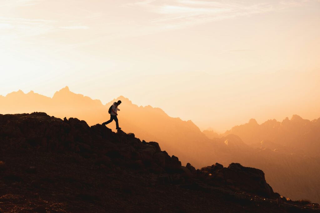 A hiker walking on a mountain ridge at sunset