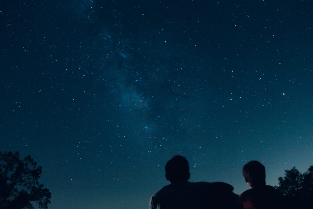 A silhouette of two people looking at the stars