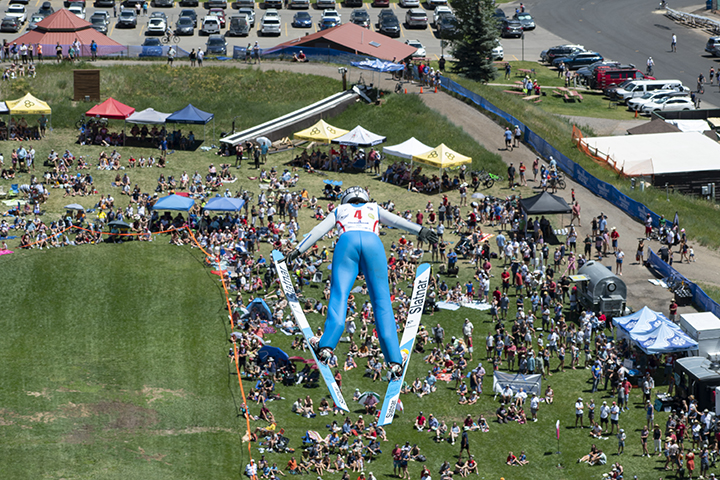A ski jumper flying over a large crowd