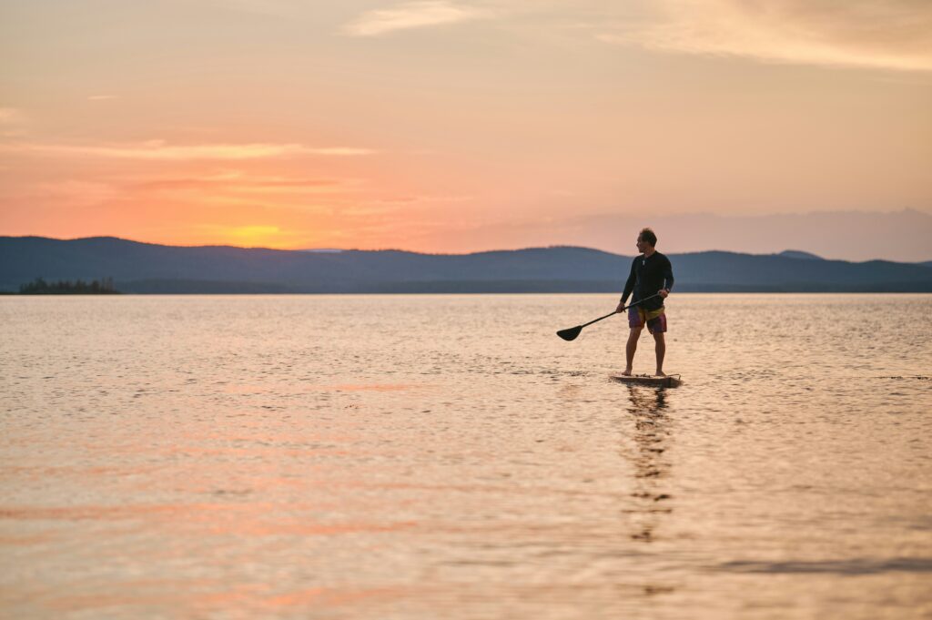 A man paddle boarding at sunset