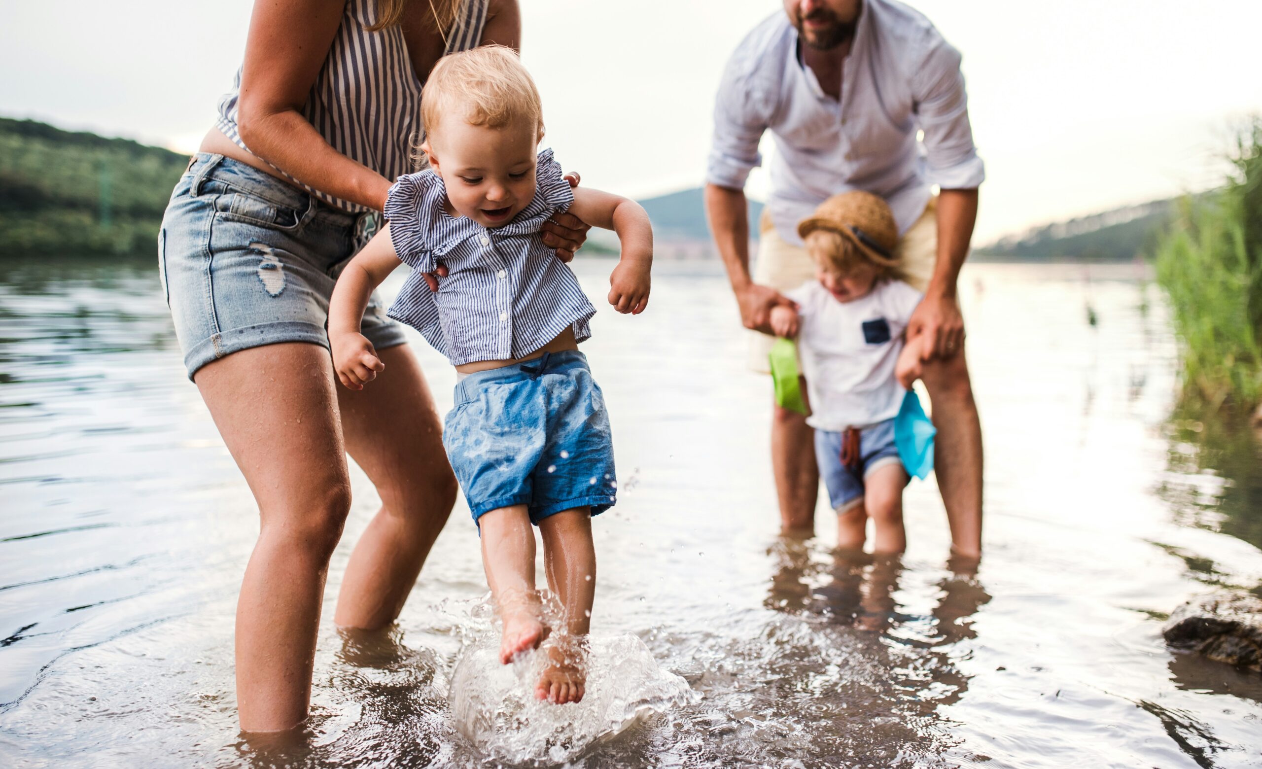 A family with two toddlers paddling in water