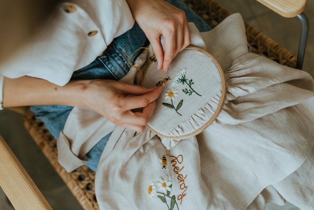 A person's hands embroidering flowers onto fabric