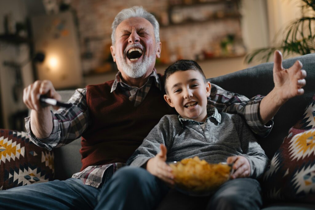 A grandfather and grandson watching a movie and laughing