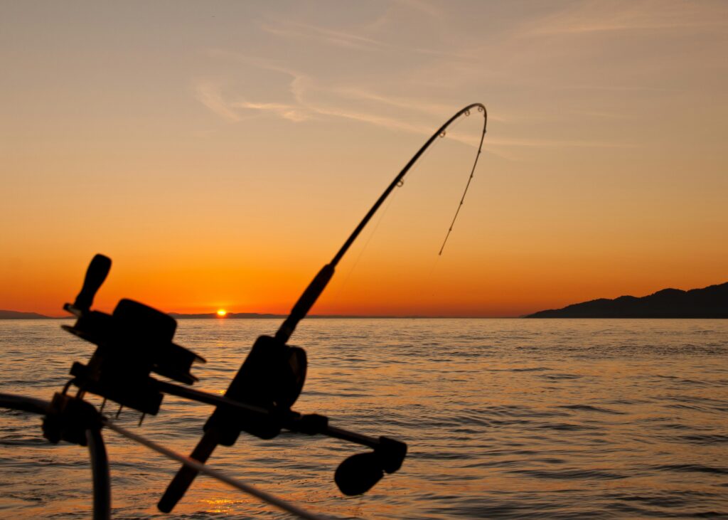 A fishing rod and a sunset over a lake