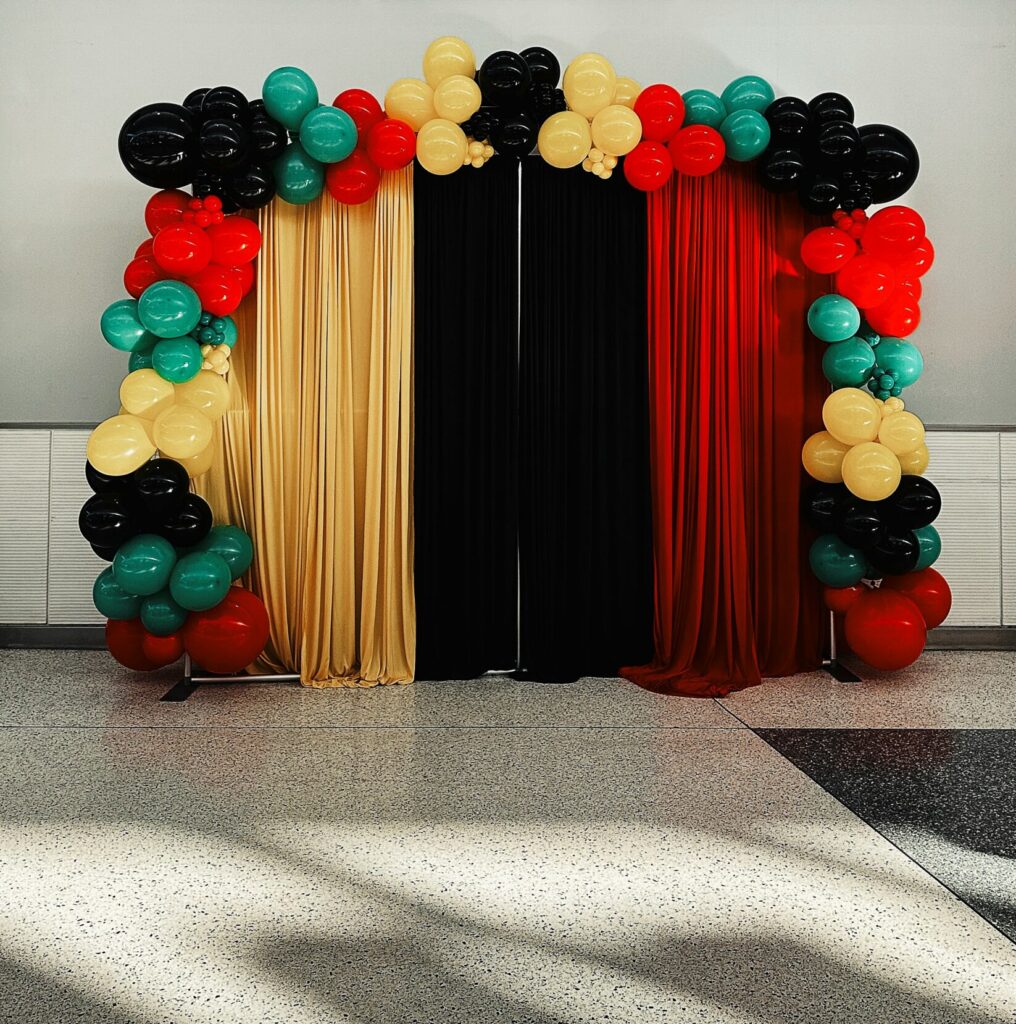 Yellow, black, red, and green balloons in an arch