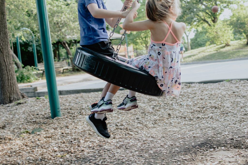 Two kids playing on a tire swing