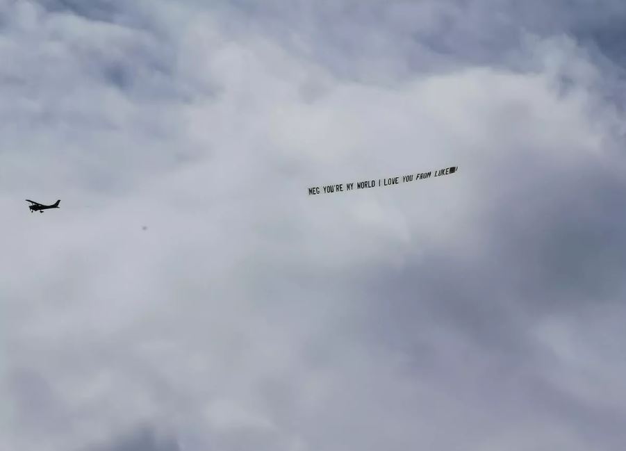 An airplane carrying a banner with a personalized message through the sky