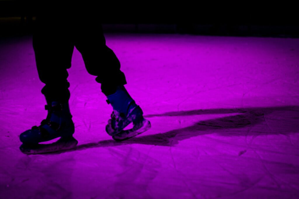 A person skating on a lit-up purple ice rink