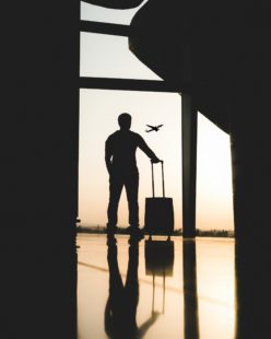 A man with a suitcase watching an airplane fly