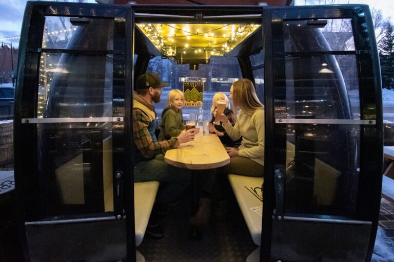 Family of four sitting in a refurbished gondola at Mountain Tap Brewery. Part of the Brew Trail in Steamboat Springs.