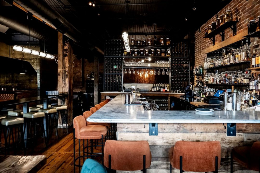 View of Laundry's bar area with cozy seating, a wall of liquor bottles, and rustic decor. They are part of the Restaurant Week event in Steamboat Springs in October.