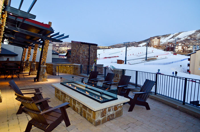 View of Truffle Pig's patio with a fire table, Adirondack chairs, and a view of Mt Werner. 